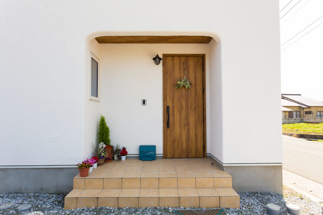 白い塗り壁に木の玄関ドア
